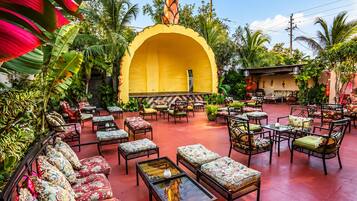 An outdoor seating area with wicker furniture and a yellow arch structure.