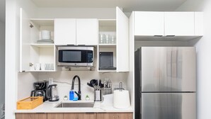 Een moderne keuken met witte kasten, een roestvrijstalen koelkast, een magnetron en een koffiezetapparaat.