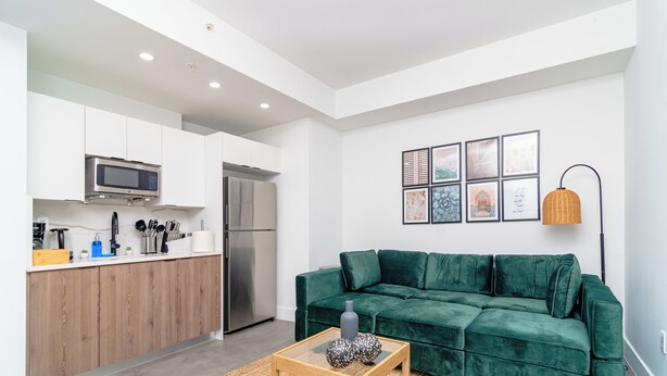Een moderne woonruimte met een keuken, een groene bank en een salontafel.