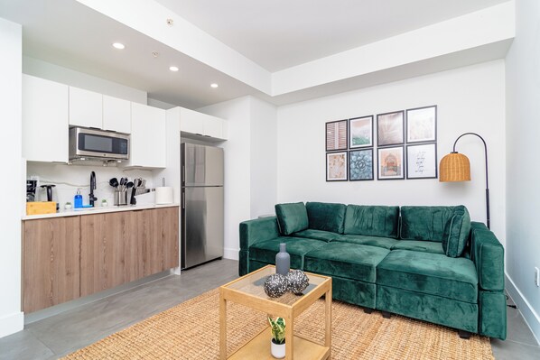 Un espace de vie moderne comprenant une cuisine, un canapé vert et une table basse.