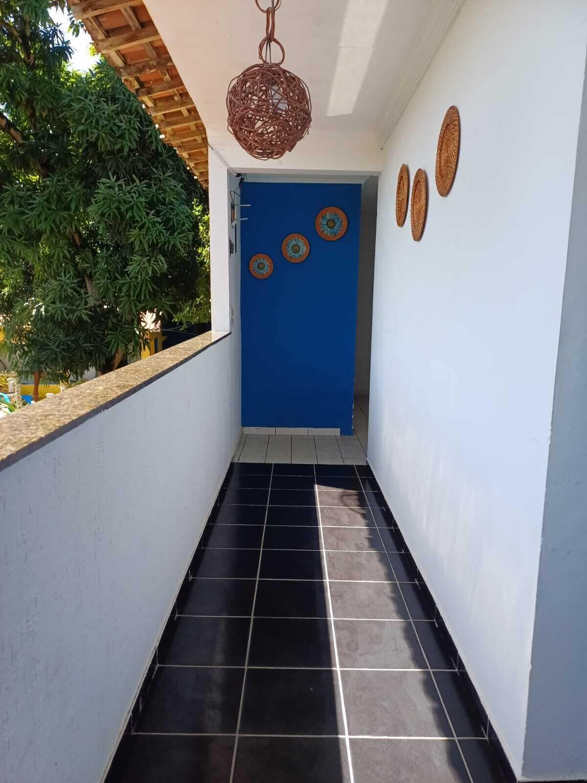 A narrow hallway with black tiled flooring, a blue door, and decorative plates on the wall.