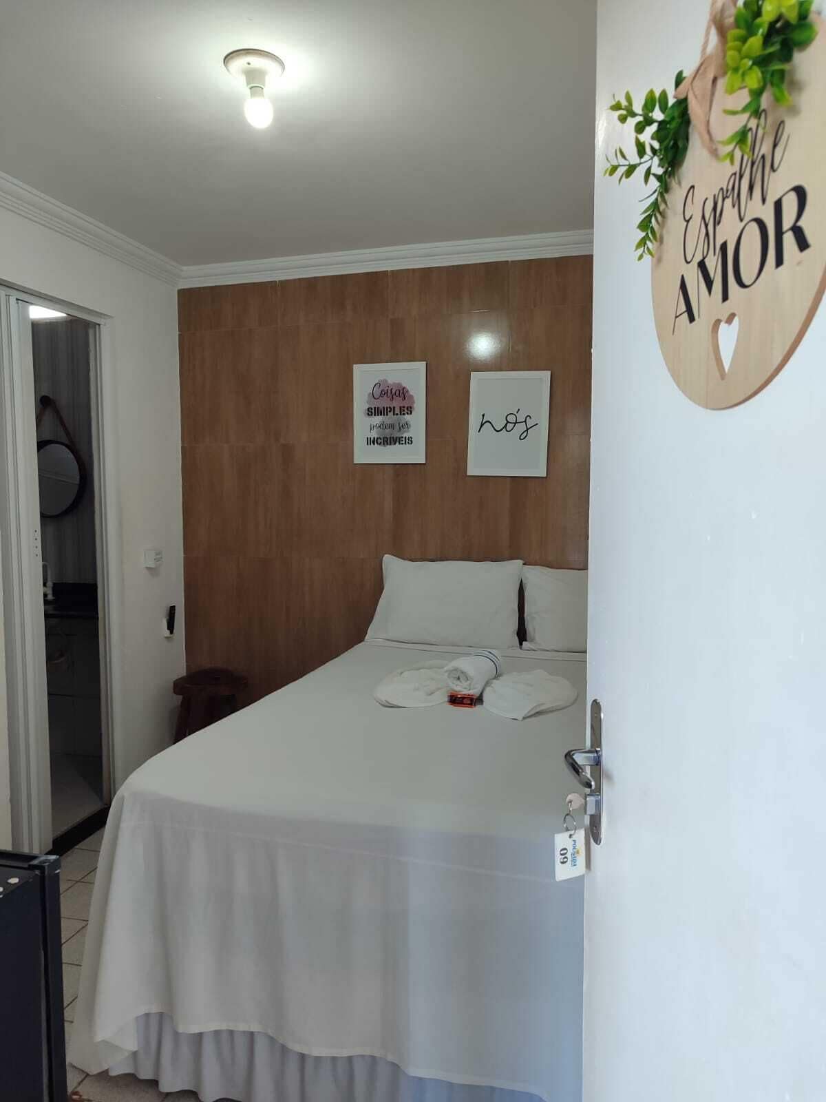 A bedroom with a bed, a wall-mounted sign, and a door to a bathroom.