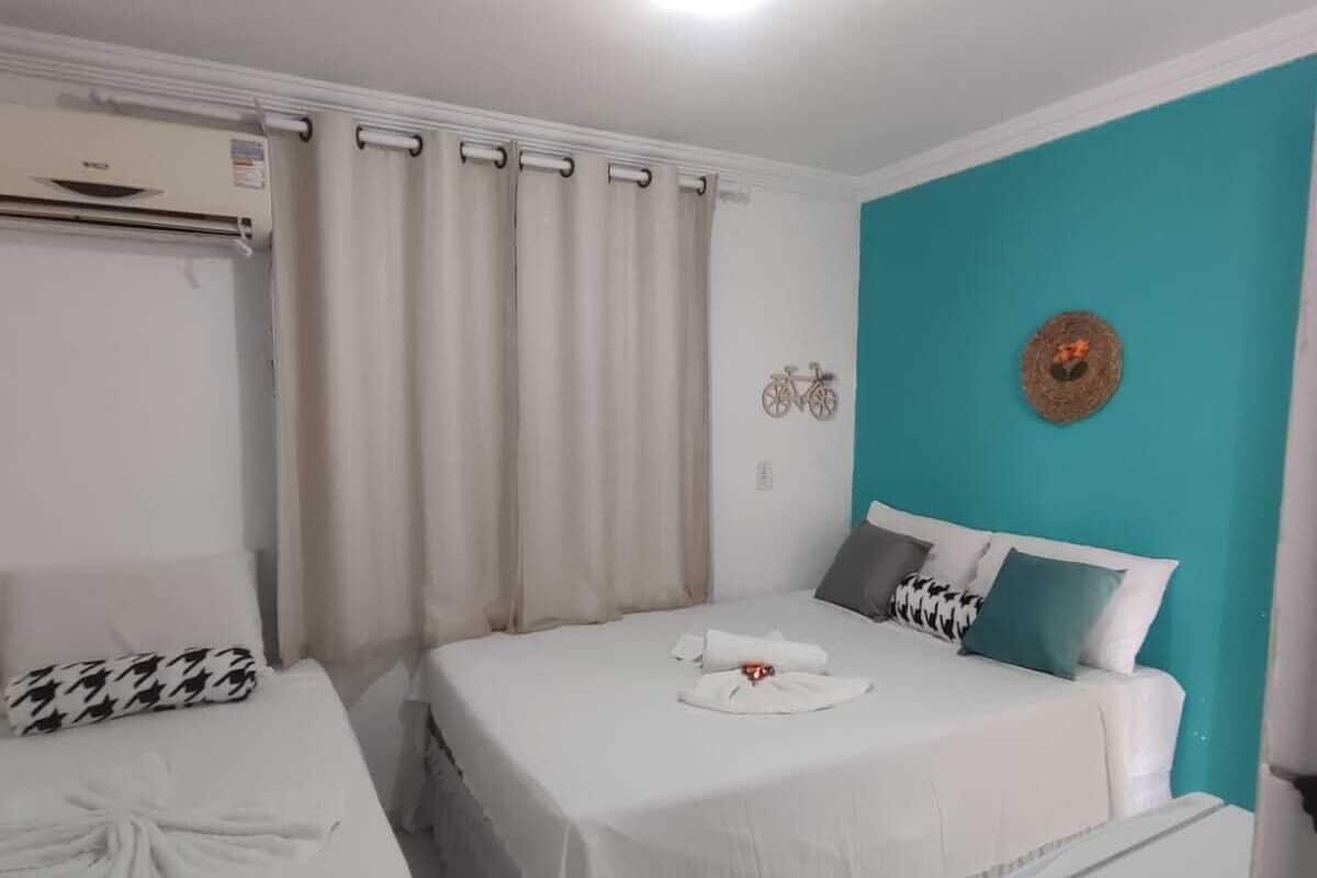 A hotel room with two beds, a teal accent wall, and a ceiling fan.