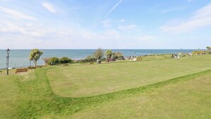 Ein Golfplatz mit Blick auf den Ozean, Bänken und blauem Himmel.