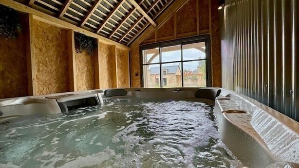 A hot tub with a wooden ceiling and large windows.