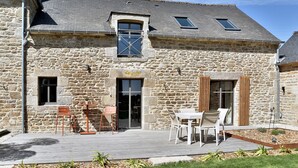 A stone building with a wooden deck, outdoor seating, and a small garden area.