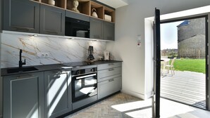 A modern kitchen with grey cabinets, a marble countertop, and built-in appliances.