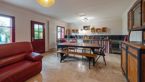 A spacious kitchen with a dining table, benches, and a red leather sofa.