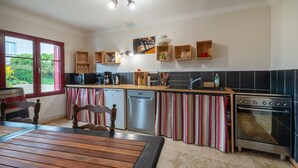 A modern kitchen with a wooden dining table, built-in appliances, and striped curtains.