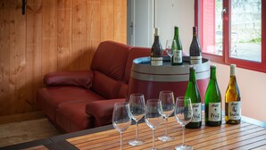A cozy room with a wooden wall, a red leather sofa, a wooden table with wine bottles and glasses, and a window with a view.