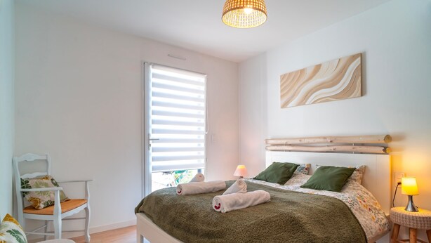 A bedroom with a bed, a chair, a lamp, and a window with blinds.