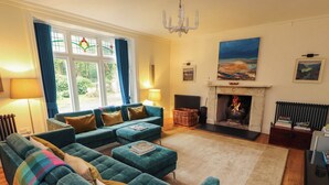 Una sala de estar acogedora con un sofá modular, una chimenea y un ventanal con cortinas.