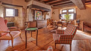 A rustic room with wooden floors, a billiards table, a fireplace, and a television.