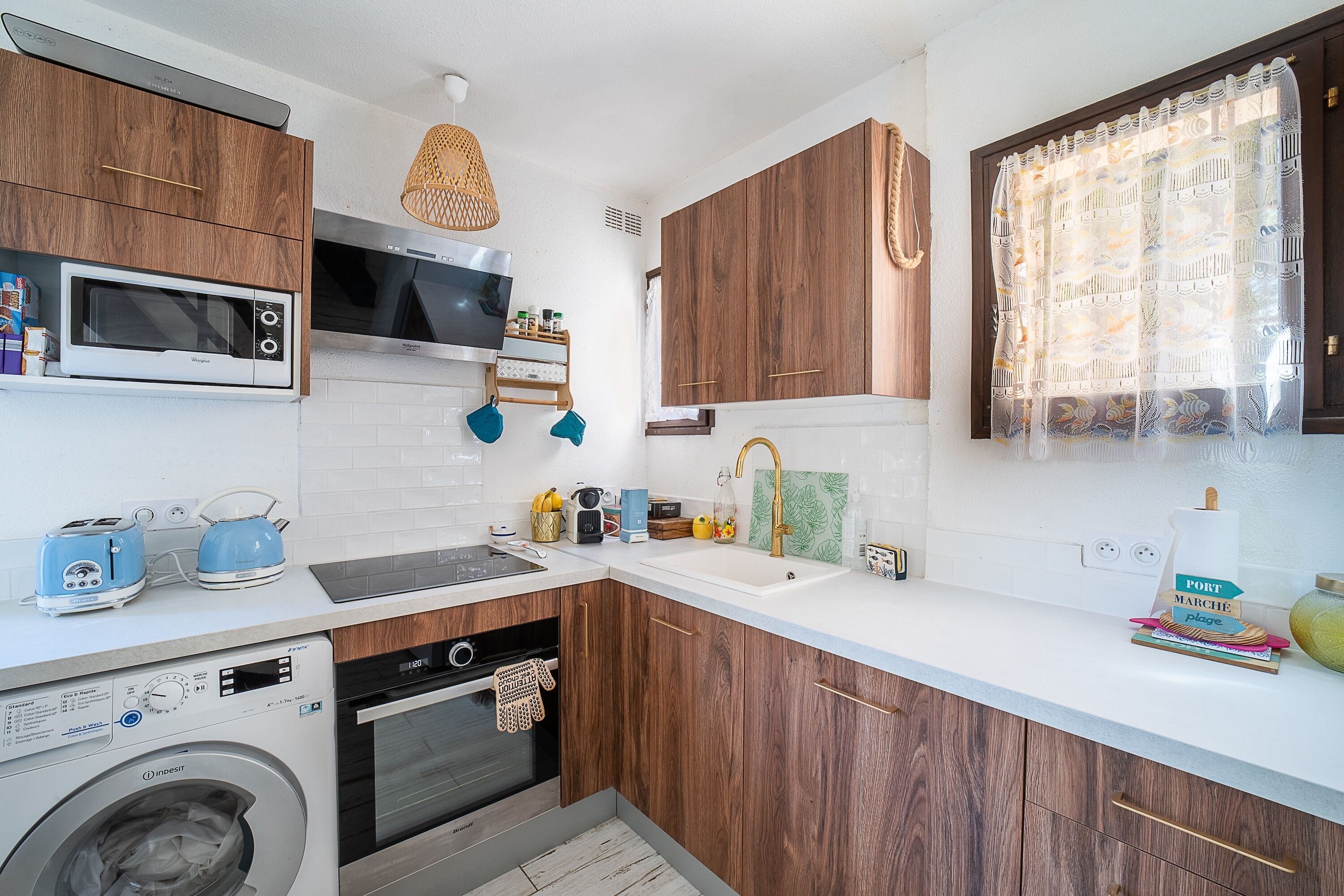 Une cuisine moderne avec des meubles en bois, un four à micro-ondes encastré, un lave-linge et un évier.