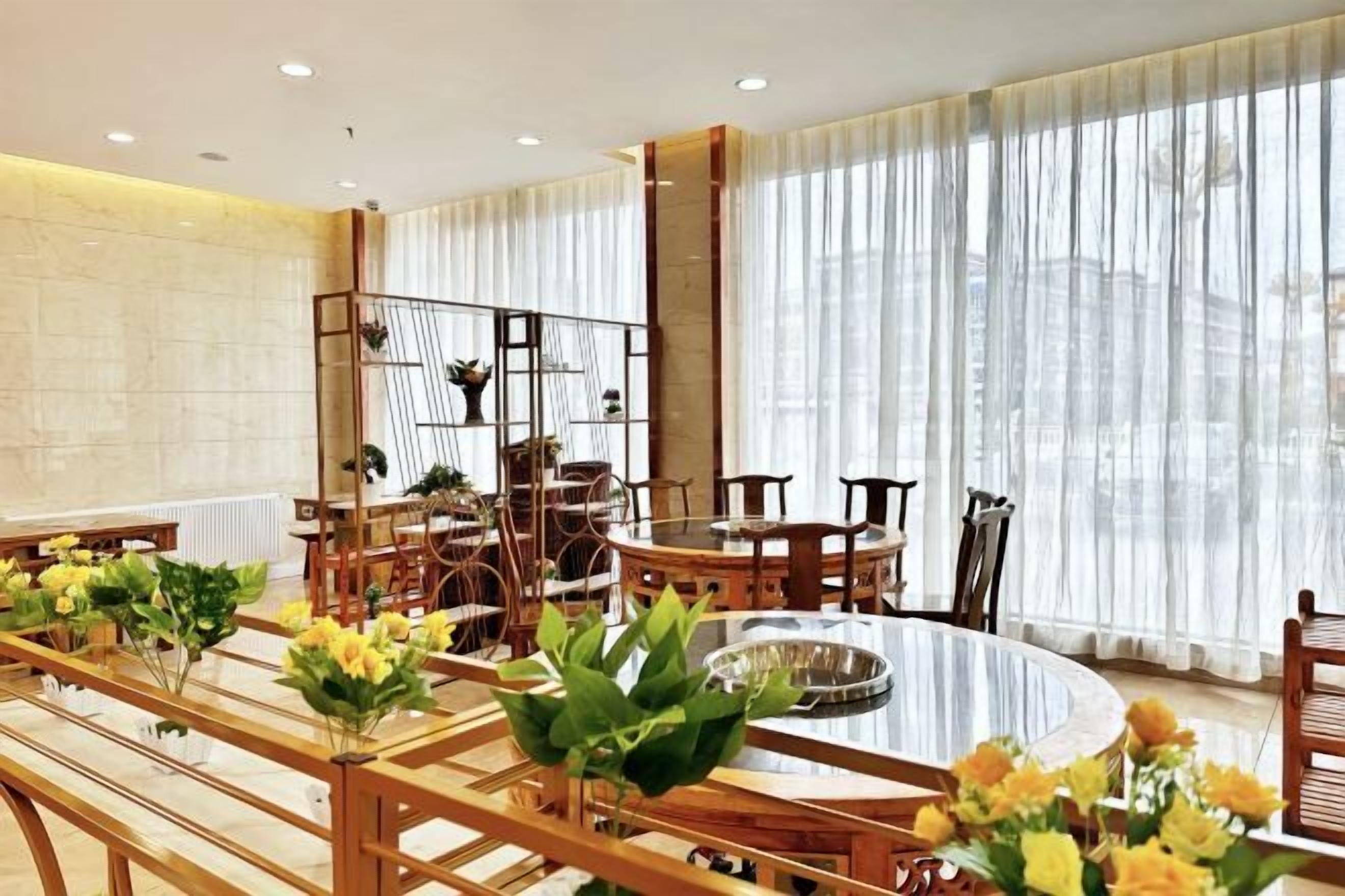 A dining area with a round table, chairs, and potted plants.