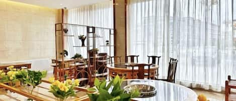 Un comedor con una mesa redonda, sillas y plantas en macetas.