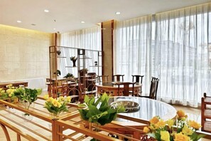 A dining area with a round table, chairs, and potted plants. - Crown Boutique Hotel (Sertar)