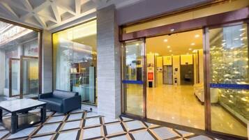 Un vestíbulo de hotel con piso de baldosas, un sofá y un escaparate de vidrio.