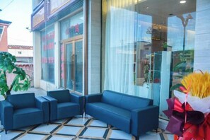 Een hotel lobby met een zithoek, een glazen gevel en een betegelde vloer.