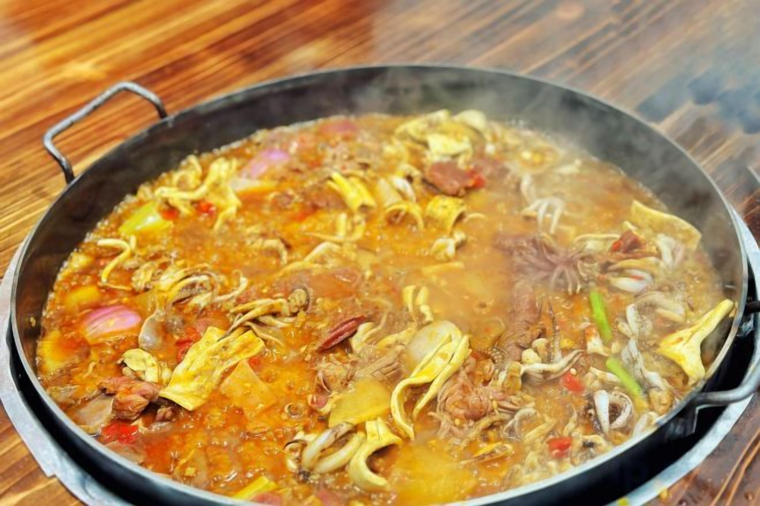 Una olla grande llena de un guiso con diversos ingredientes.