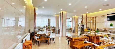 A hotel lobby with a modern design, featuring a marble reception desk, wooden furniture, and a large window providing natural light.