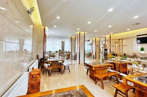 Un vestíbulo de hotel con diseño moderno, que presenta un mostrador de recepción de mármol, mobiliario de madera y un amplio ventanal que proporciona luz natural.