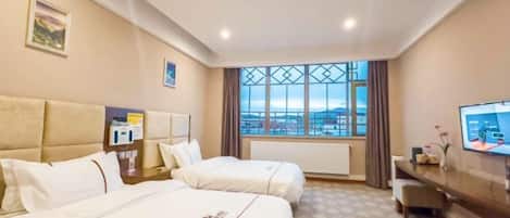 A hotel room with two beds, a television, a window with a view, and a desk with a chair.