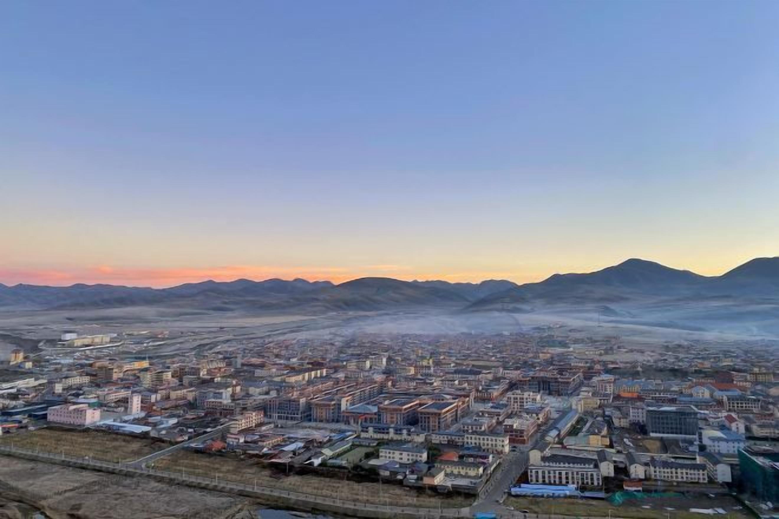 Un paisaje urbano con una vista amplia de edificios y una cadena montañosa distante.
