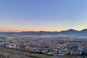 Un paisaje urbano con una vista amplia de edificios y una cadena montañosa distante.