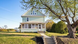 A two-story house with a front porch and a small staircase leading to the front door.