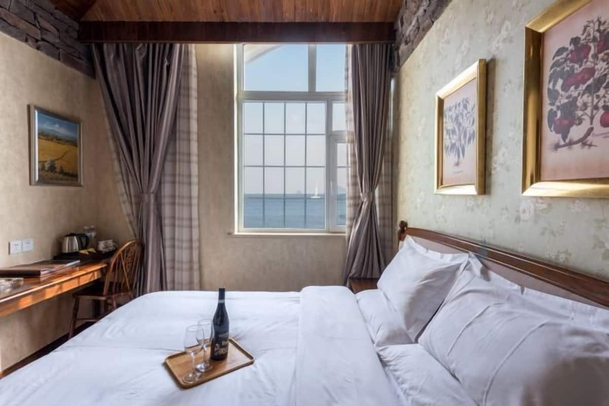Ein Hotelzimmer mit Bett, Schreibtisch und einem fensterbepflanzten Fenster.