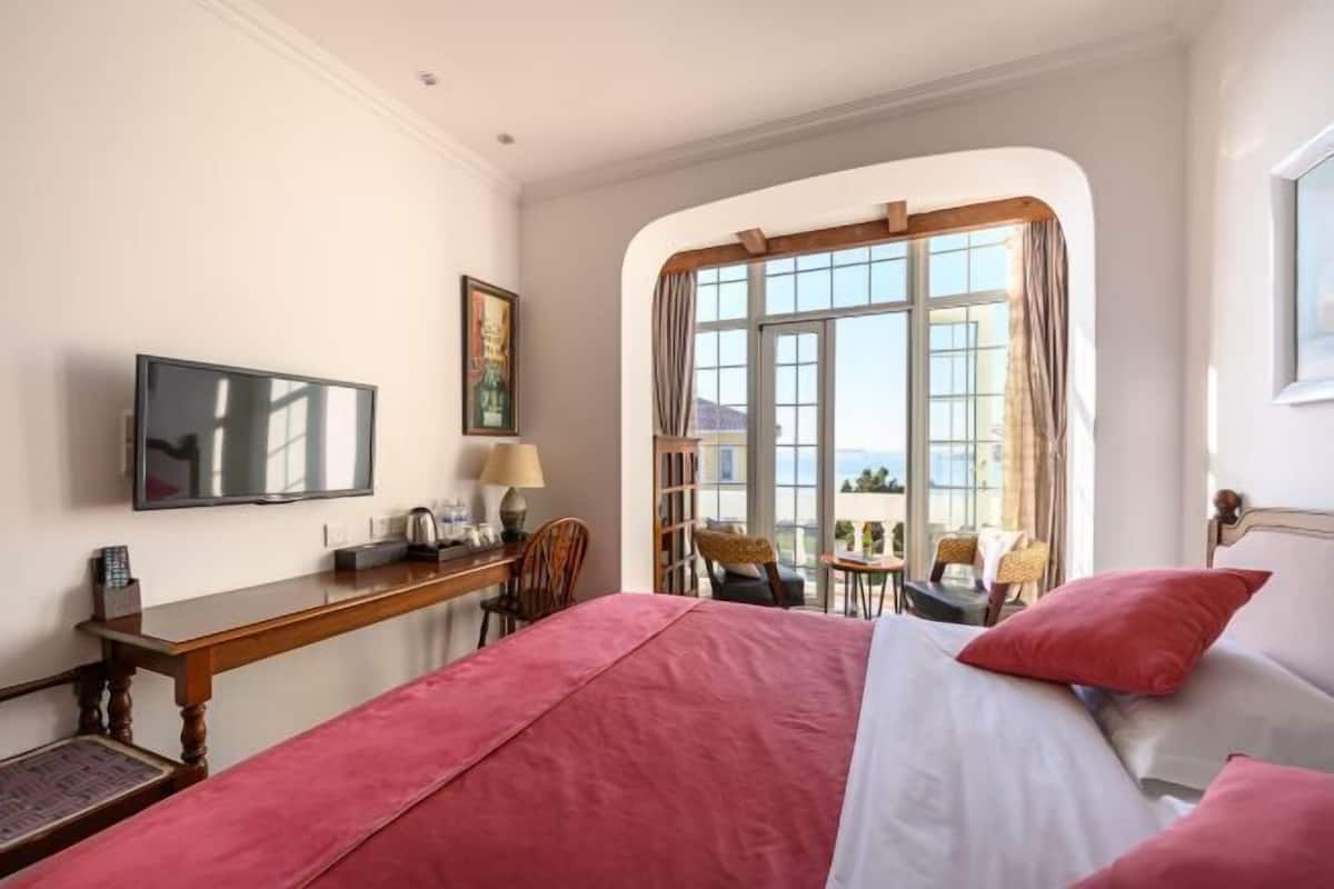 Ein Hotelzimmer mit Bett, Schreibtisch, Stuhl, Fernseher und einem Fenster mit Blick.
