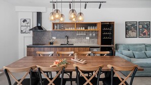 Una cocina moderna con una mesa de comedor de madera, sillas negras y lámparas colgantes.