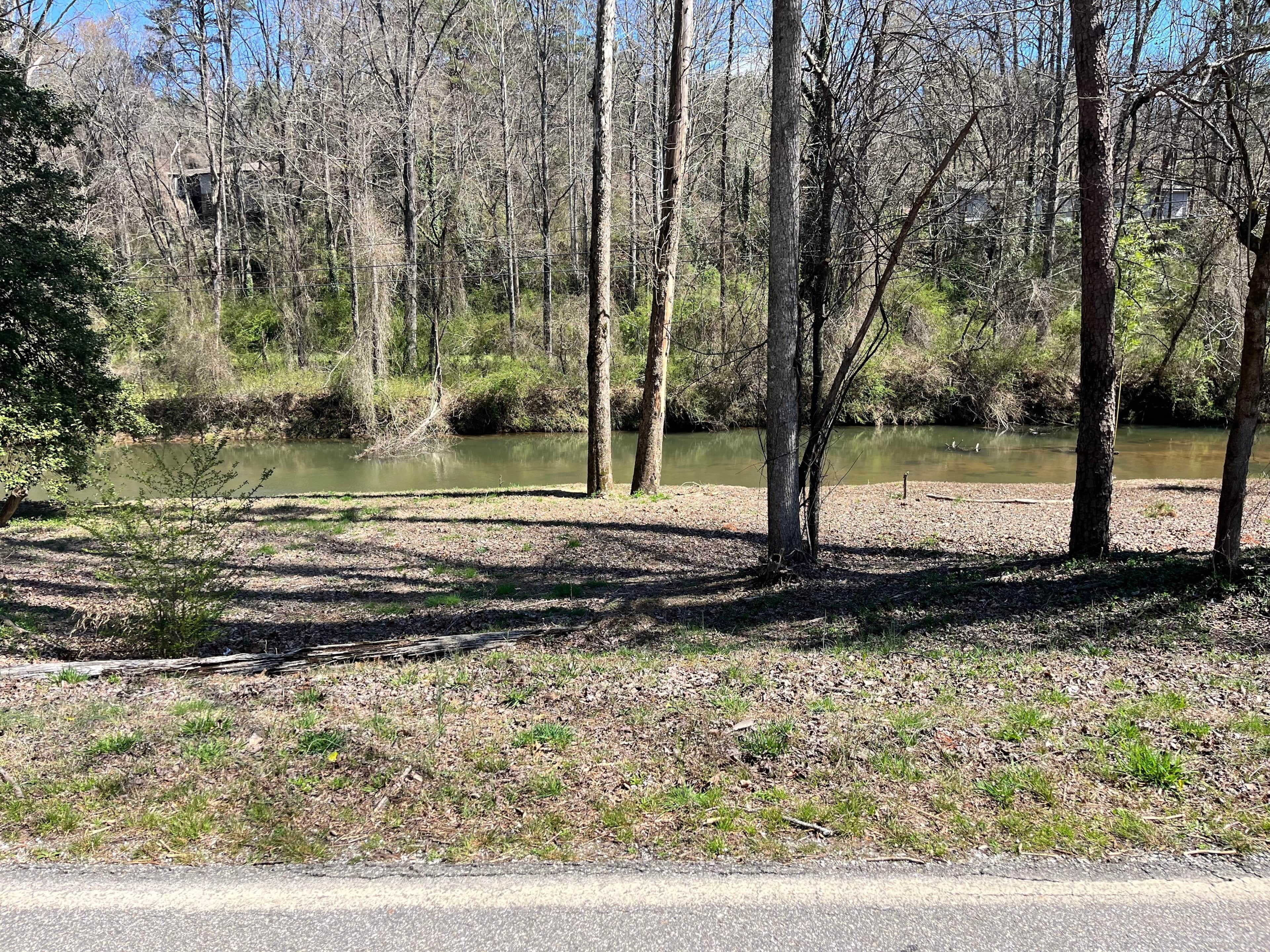 Un cadre naturel avec une rivière, des arbres et un ciel dégagé.