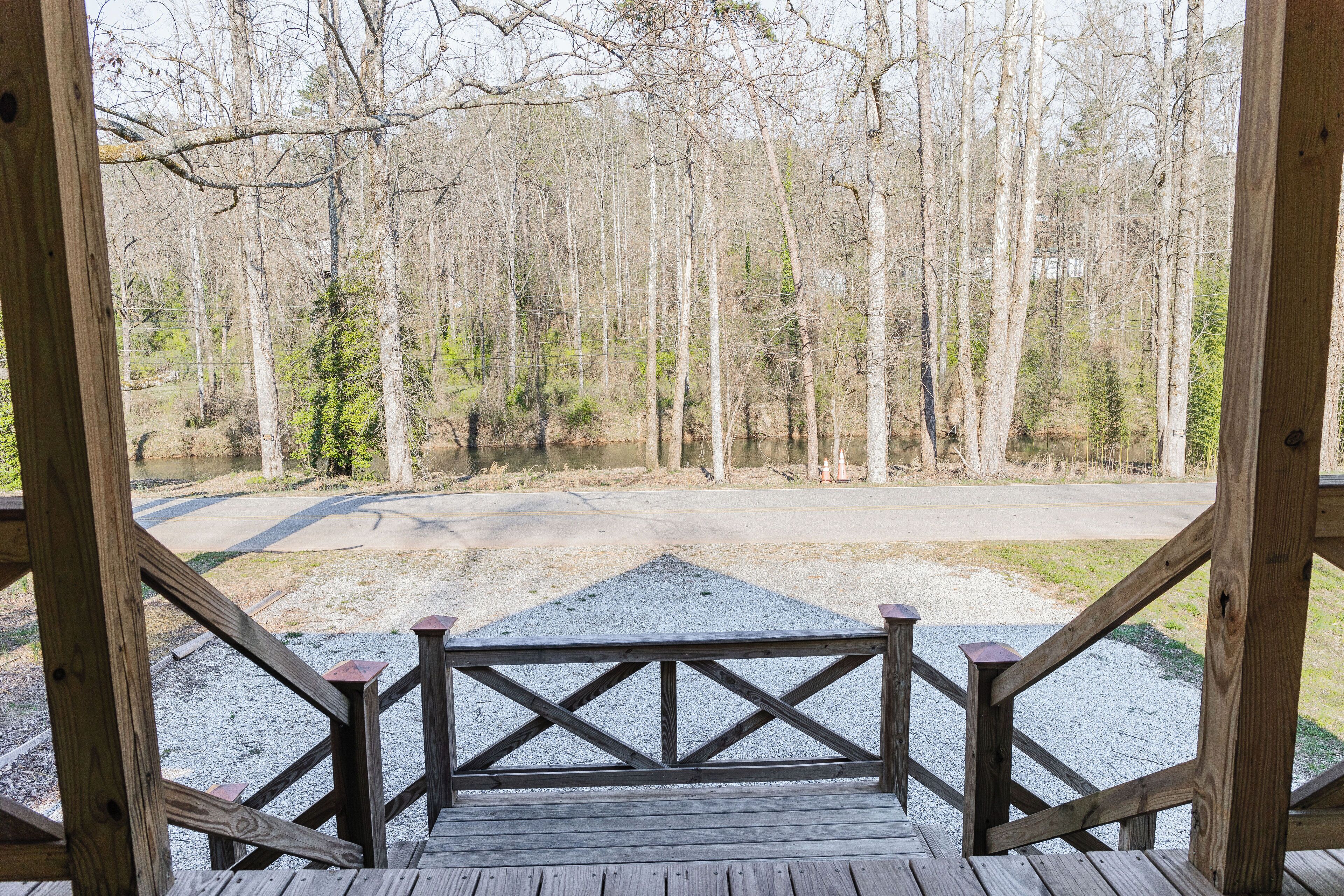 A wooden deck with a gravel path leading to a forested area.