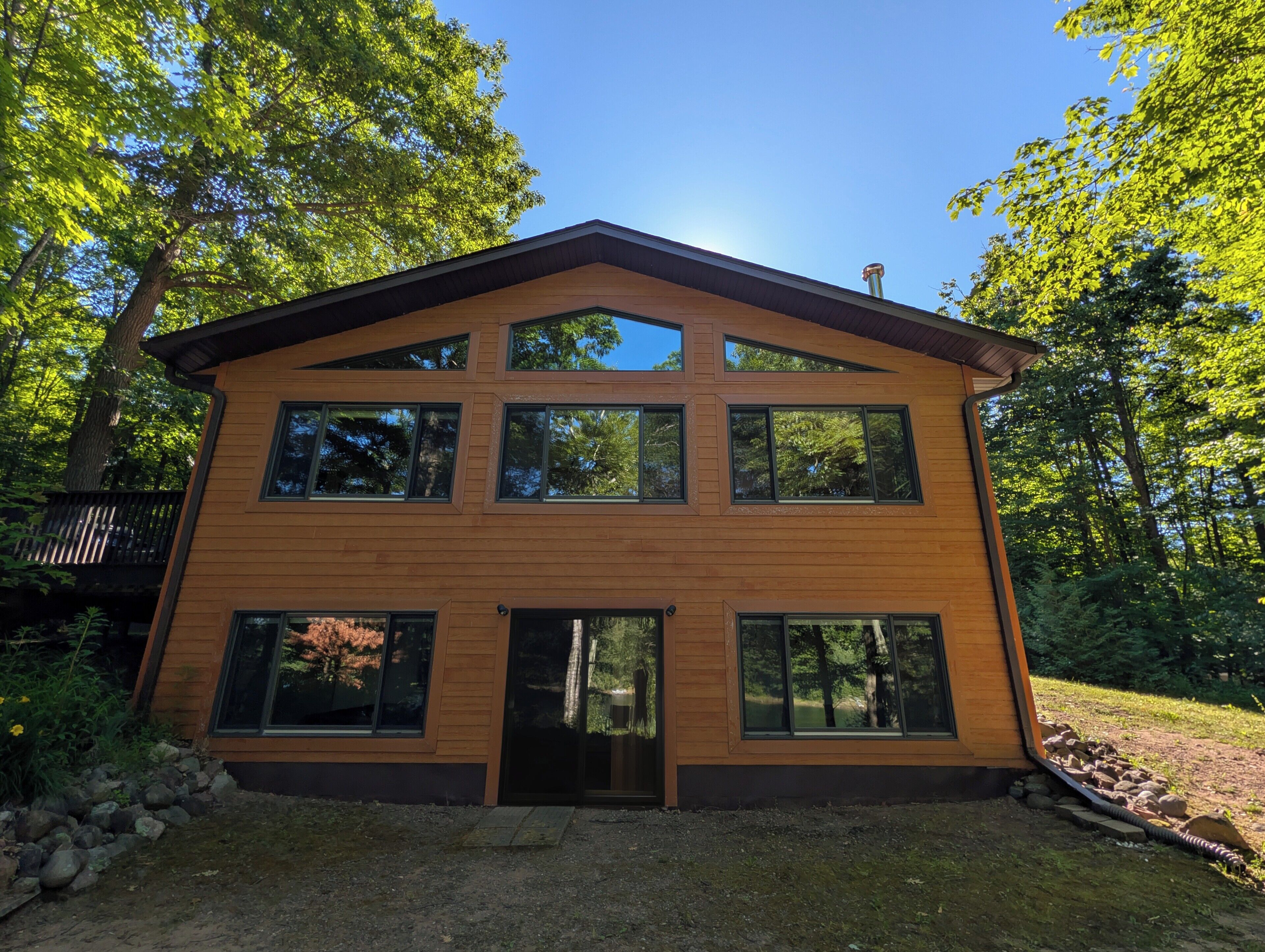 A modern two-story building with large windows and a wooden exterior, surrounded by trees.