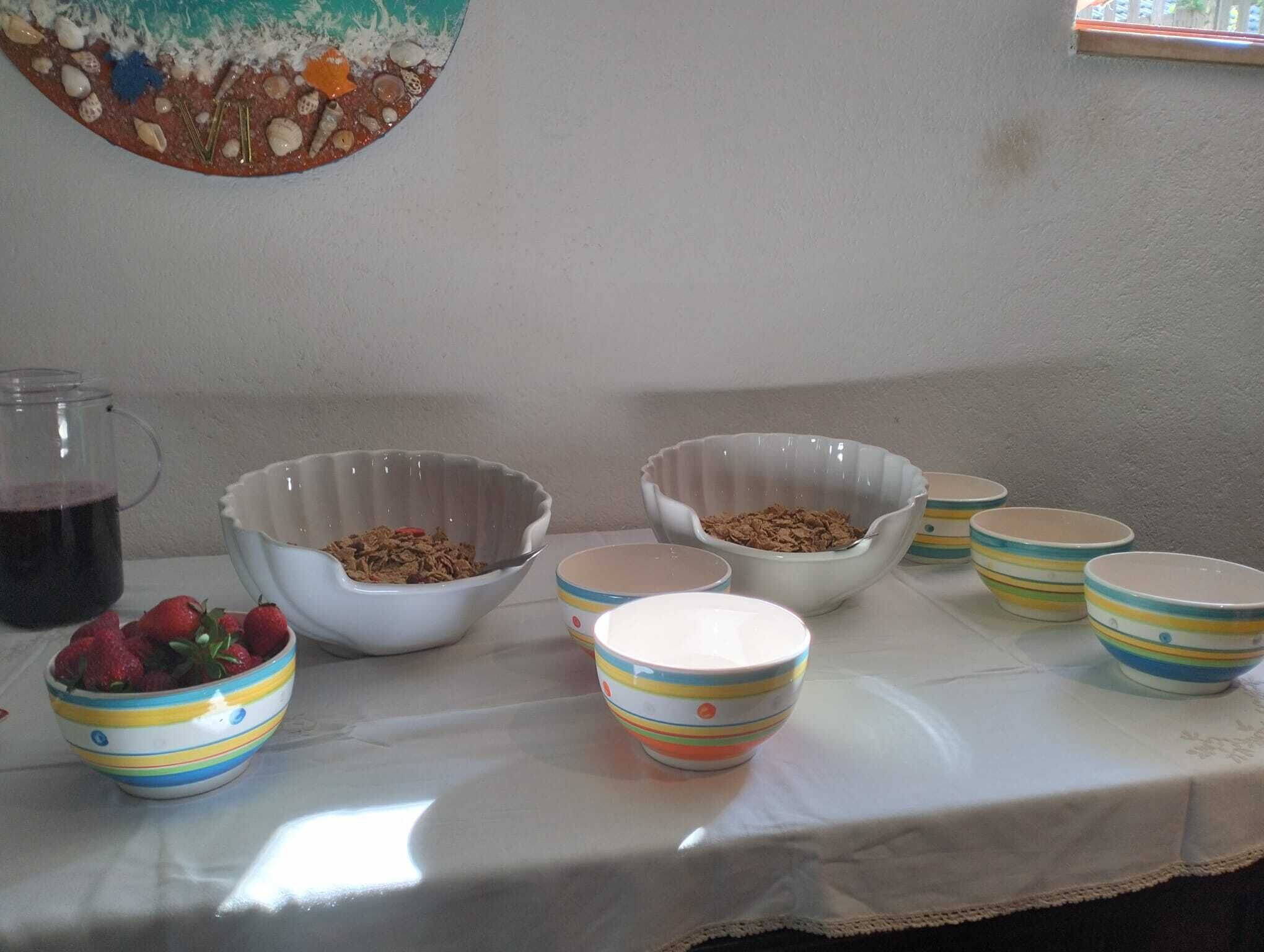 Una mesa con cuencos de comida, un tarro de cristal con un líquido oscuro y un bol de fresas.