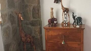 A room with a stone wall, a wooden dresser, and a giraffe sculpture.