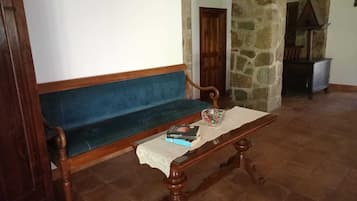 A room with a wooden bench, a small table with a lace tablecloth, and a bowl of candy.