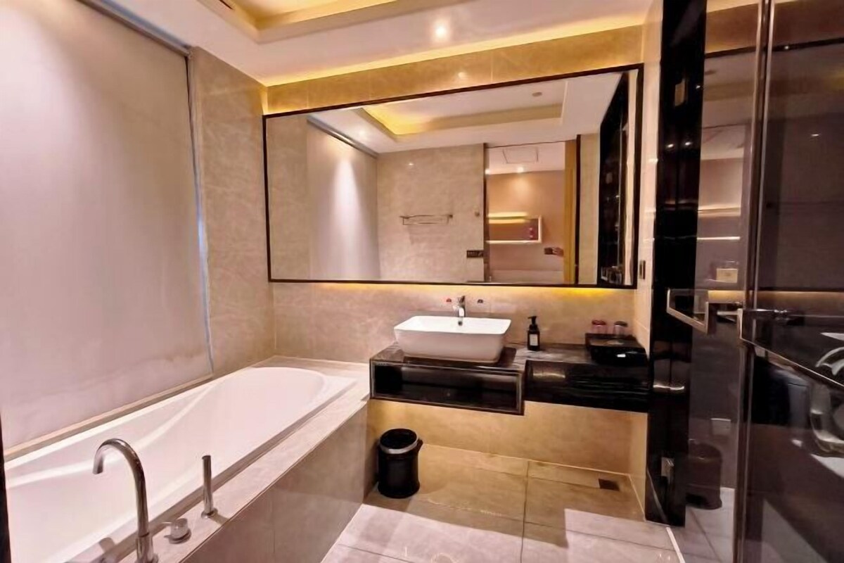 A modern bathroom with a freestanding bathtub, a vanity with a mirror, and a black countertop.
