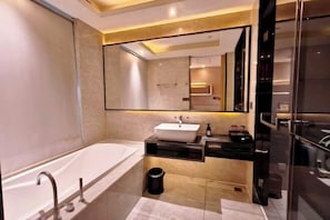 A modern bathroom with a freestanding bathtub, a vanity with a mirror, and a black countertop.