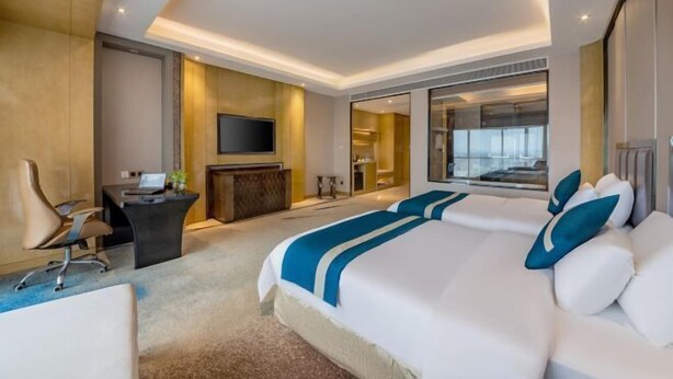Una habitación de hotel moderna con una cama grande, un escritorio, un televisor de pantalla plana y vistas a la ciudad por la ventana.