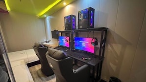 Ein Spielzimmer mit zwei Gaming-Stühlen, zwei Monitoren und zwei Computer-Türmen.