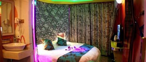A room with a bed, a sink, and a mirror.