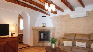 Una sala de estar con chimenea, sofá, televisor y una mesa de madera.