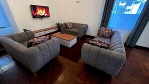 Ein Wohnzimmer mit zwei grauen Sofas, einem Holztisch und einem an der Wand befestigten Fernseher.