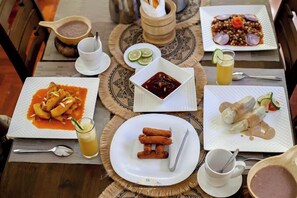 A dining table with various dishes, including a plate of enchiladas, a bowl of soup, and a plate of rice with vegetables. There are also condiments and drinks on the table. - El Tesa Court Gardens Milimani (Kisumu)