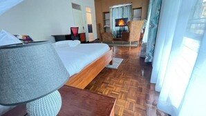 Ein Hotelzimmer mit Bett, Fernseher, Kamin und Blick ins Freie.