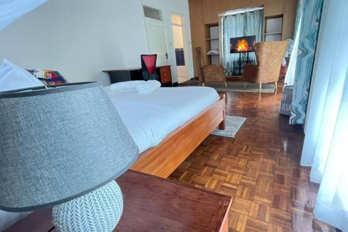 Ein Hotelzimmer mit Bett, Fernseher, Kamin und Blick ins Freie.