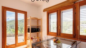 Eine Küche mit Glastisch, Holzschränken und Blick auf eine bewaldete Landschaft.